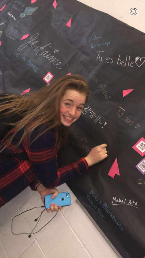 Sophomore and second year French student Megan Foster writes on the Wall of Love in the cafeteria.