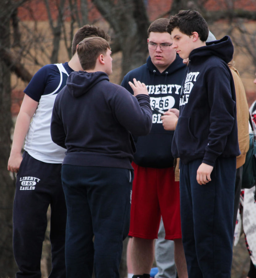 Blake Degner (middle) listens to newer throwers at a meet.