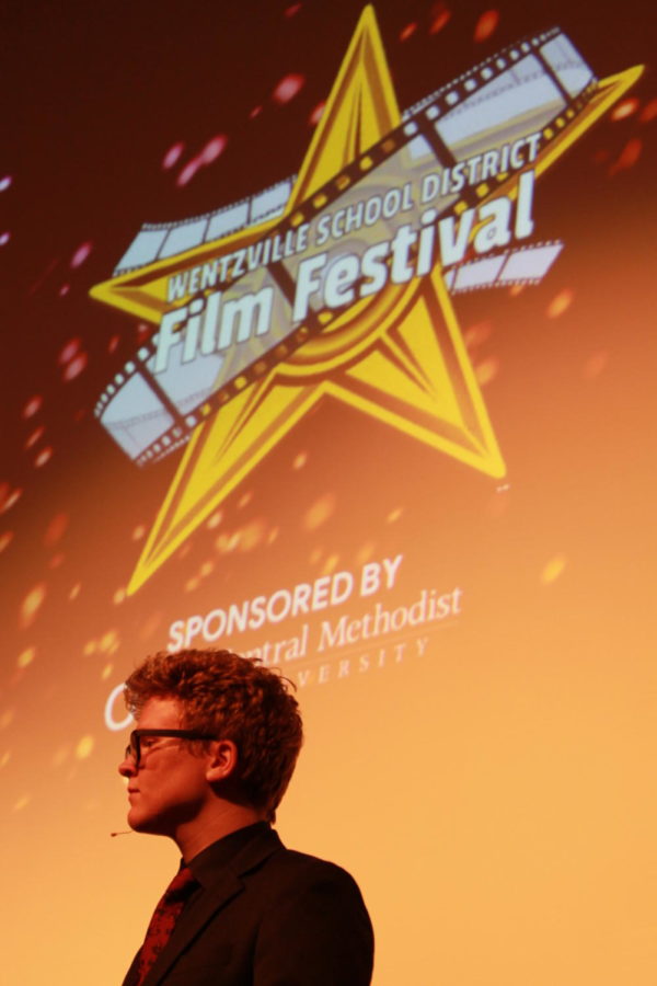 Host stands in front of screen on the stage at Holt High School during the WSD Film Festival on April 2. 