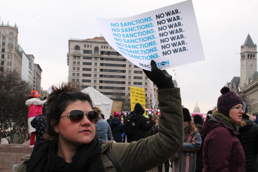 A protestor holds a sign declaring peace and no war before the Womens March starts.