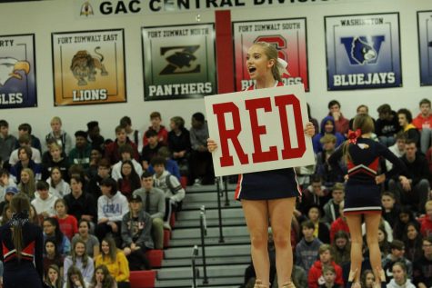 Flyer and junior Bailey Crow holds up a RED sign during the cheer routine at the pep assembly.