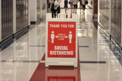 Bright red signs can be seen throughout every major hallway, requesting students and staff to socially distance.