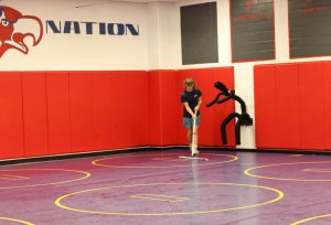 Junior Dominik Bishop mops the mats before wrestling practice begins.