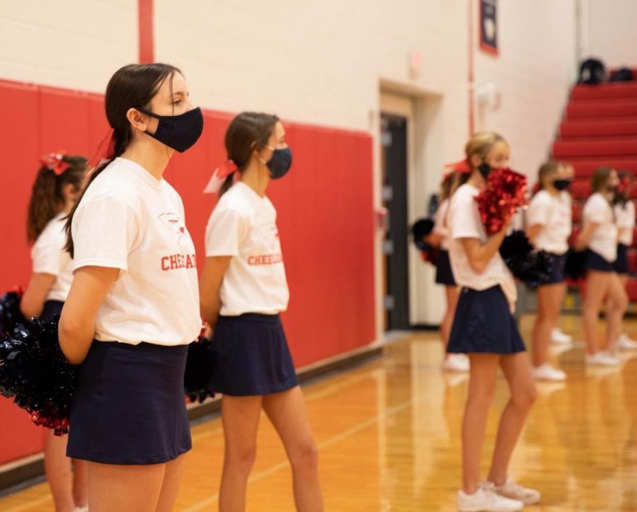 Cheerleaders stand on the sidelines during a play in the game.