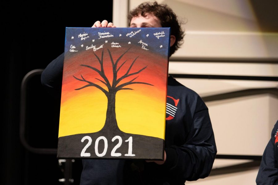 Cole Allen shows the audience the canvas that the senior choir students painted for Ms. Kennedy.