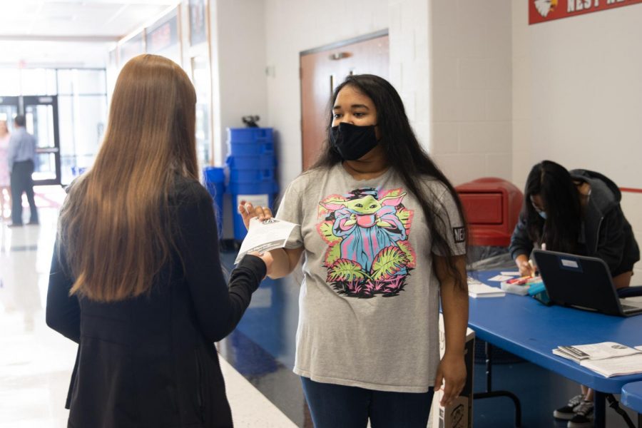 Sruthi Ramesh (12) gives a Key Club flyer to a new student.
