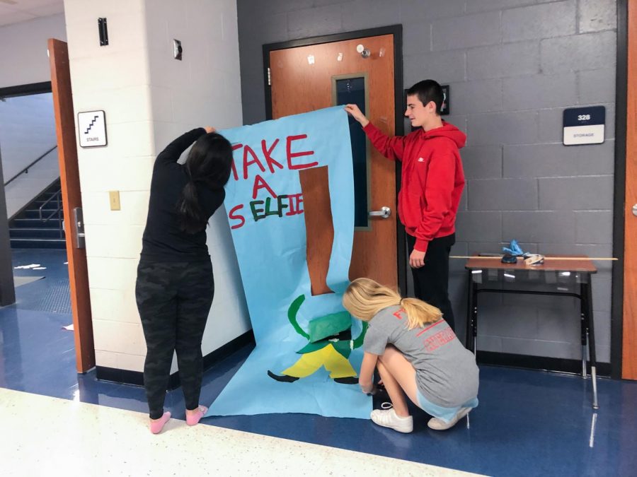 Aleigha Schnable (12), Brody Marino (9), and Carly Torbit (12) work together to hang up a decoration for Mr. Tutterows door.