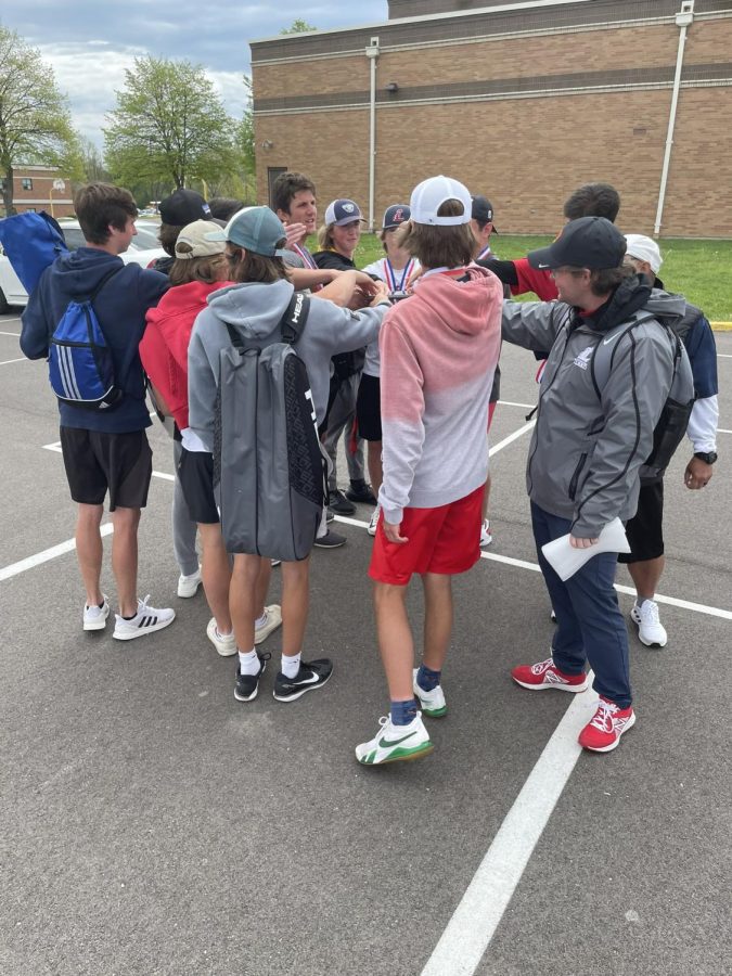 The boys tennis team huddles to chant after receiving medals and the GAC champion title plaque. 