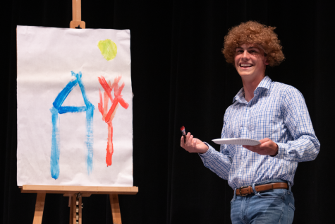 Senior Carson Clay paints on the stage of Mr. LHS while he emulates the soothing voice of Bob Ross.