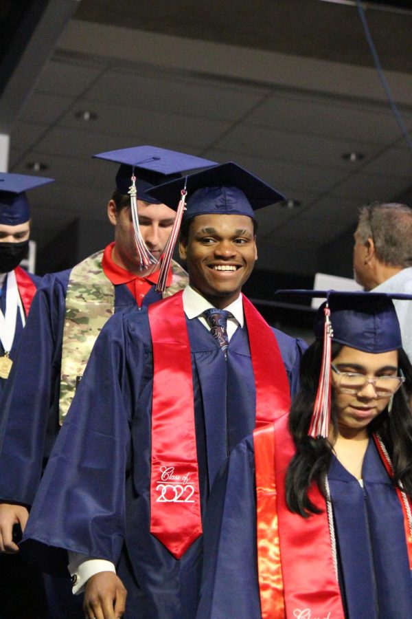 Deion Cunningham smiles to the crowd during the processional as the graduates enter the Family Arena. 