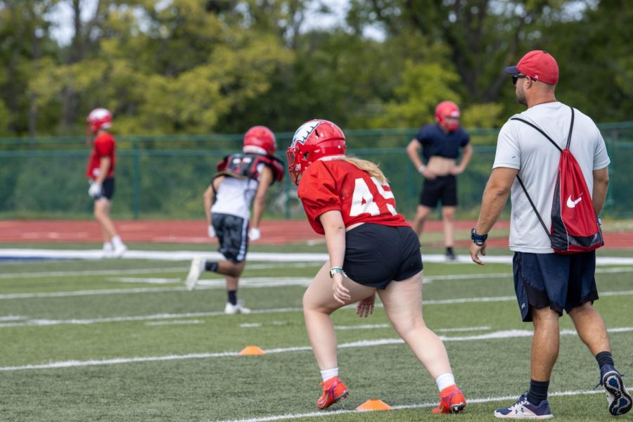 Jersey Goodall (left) in her #45 training jersey completing sprints while Head Coach Ryan McMillen (right) instructs and oversees the process.