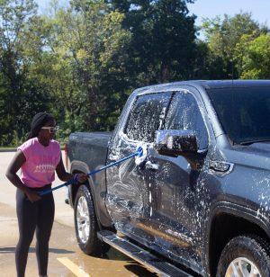 Janet Munsangali washing a truck with a mop. 