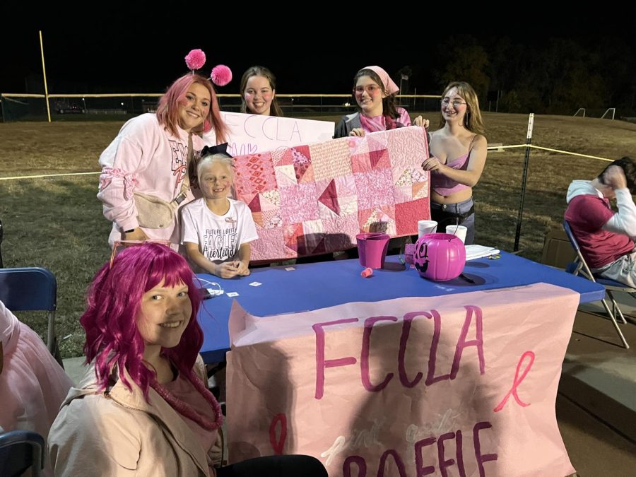 Liberty+FCCLA+members+pose+with+their+table+selling+raffle+tickets+for+a+handmade+pink+quilt.