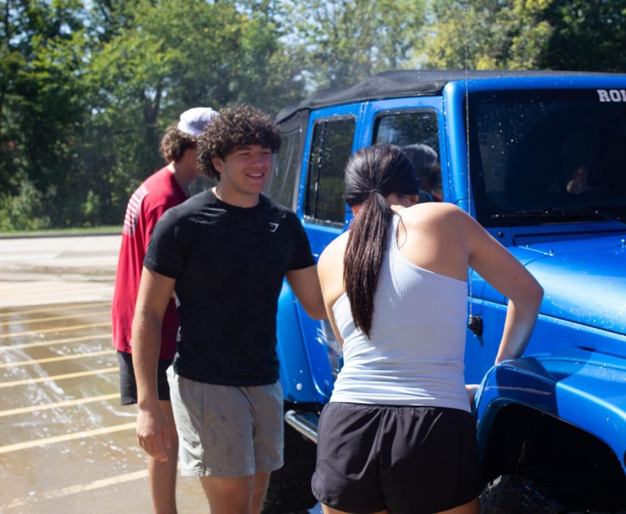 Aidan Berry, Jack Ryan and Alyse Gorman laugh and work together to wash a jeep.