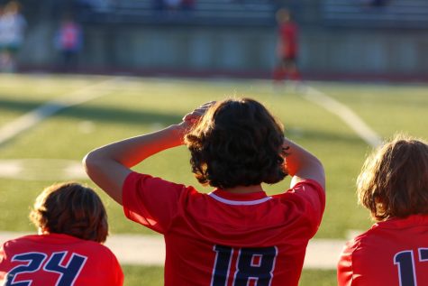 Junior, Bryson King, watches the team play from the sidelines, through the blinding sun.