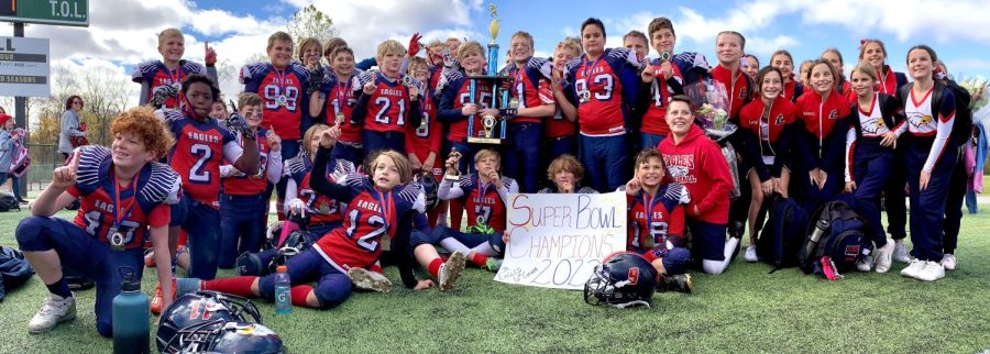 Sixth grade Junior Eagles football and cheer pose with their Super Bowl trophy after winning.