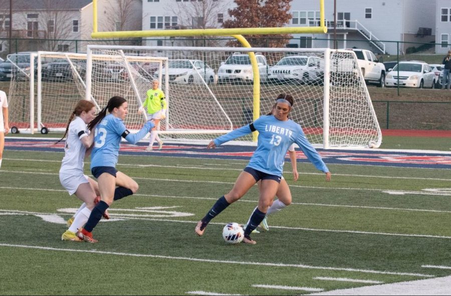 Morgan Struttmann (#13) keeps possession of the ball and tries to advance the play as Rachel Skyberg (#23) begins make a run.