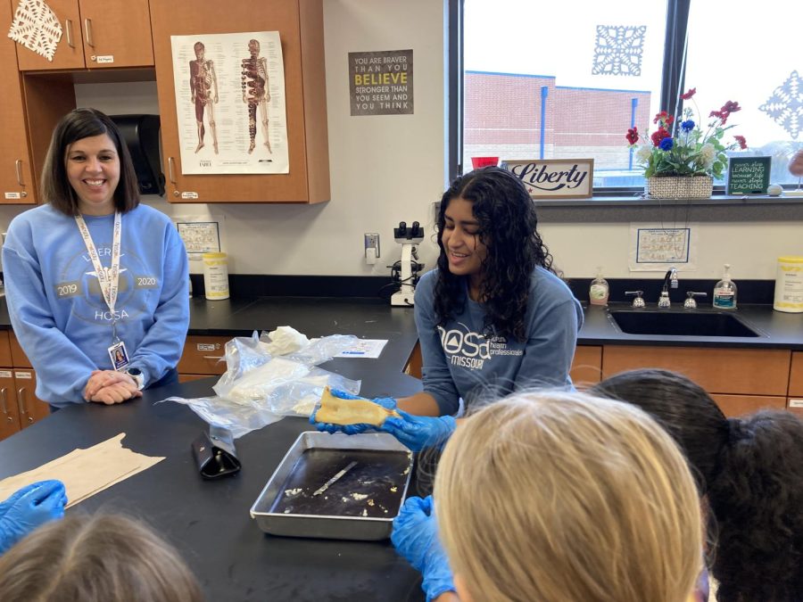 At one station, students watch as junior Emma Thomas demonstrates the dissection of a bone while teaching about parts of the bone like bone marrow.