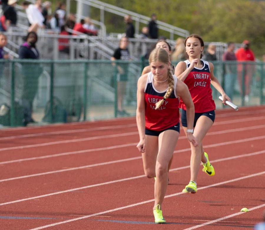 Diana Kemp (9) prepares to take the baton from Addy Long (9) in the 4x200-meter relay in a meet at Liberty. 
