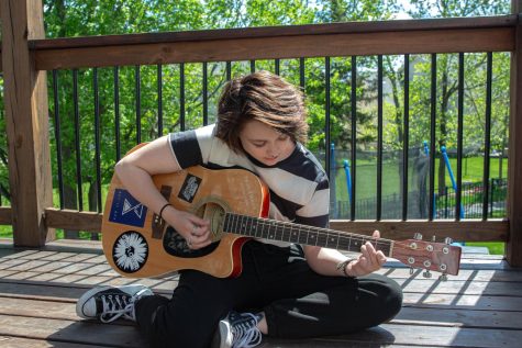 Alix Queen (12) sits on their porch while playing guitar. 