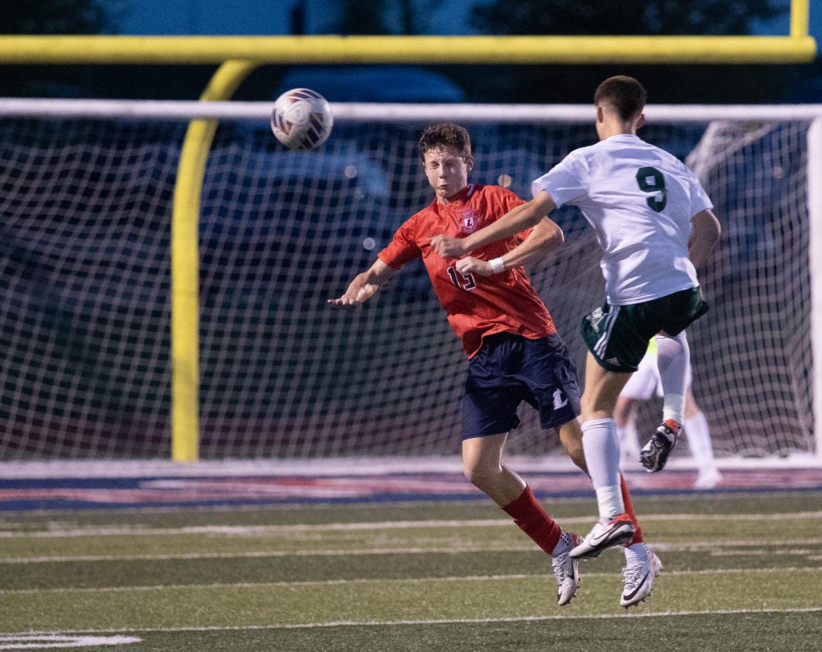 Senior Layton Dahl, repping #13 on the field, heads the ball away from a Mehlville defender. 