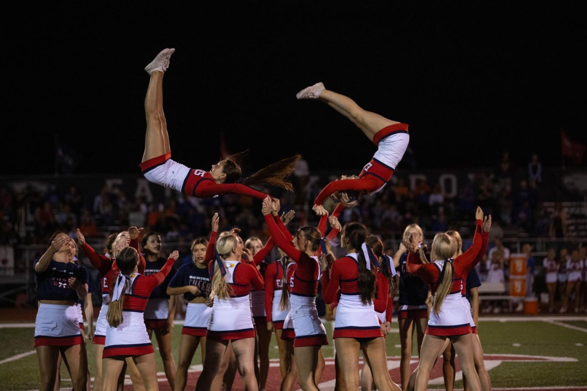 Varisty cheerleaders perform a stunt during their halftime performance for the first home game. 