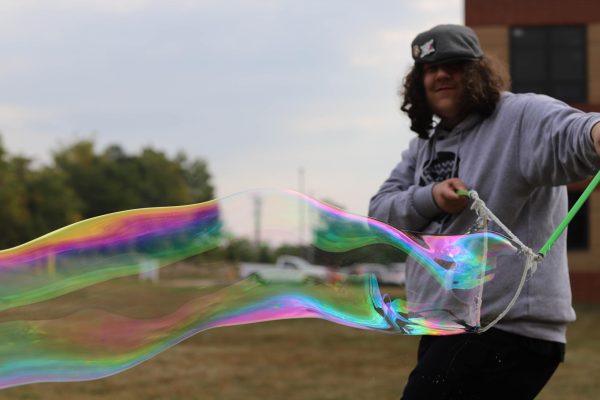 Aidan Zumwalt has fun by making giant bubbles outside during class.