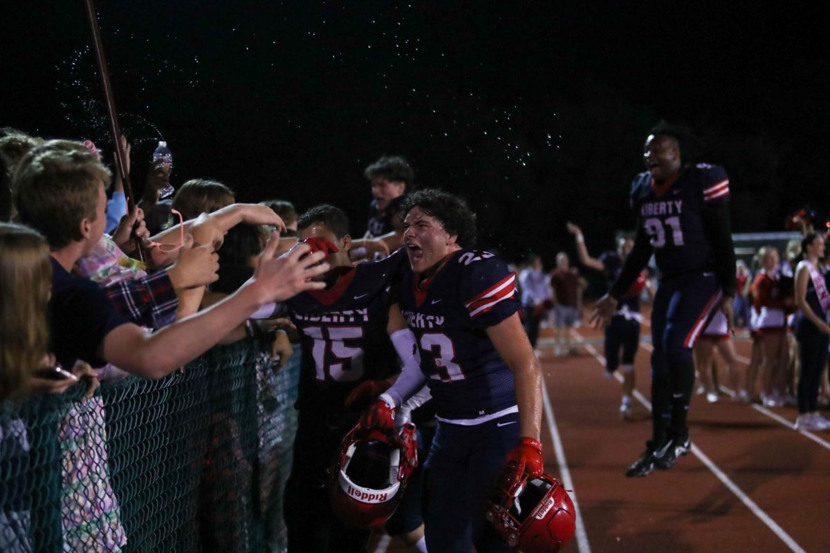 Junior Jack Ryan, representing number 23 on the field, cheers loudly with the student section, celebrating the win against North Point High School. He does so while holding his helmet alongside senior Ivan Marin. 