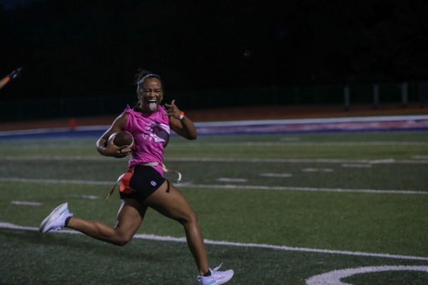Senior Grace Edney looks over to her fellow teammates as she runs with the football and scoring a touchdown during the annual Powder Puff game. 