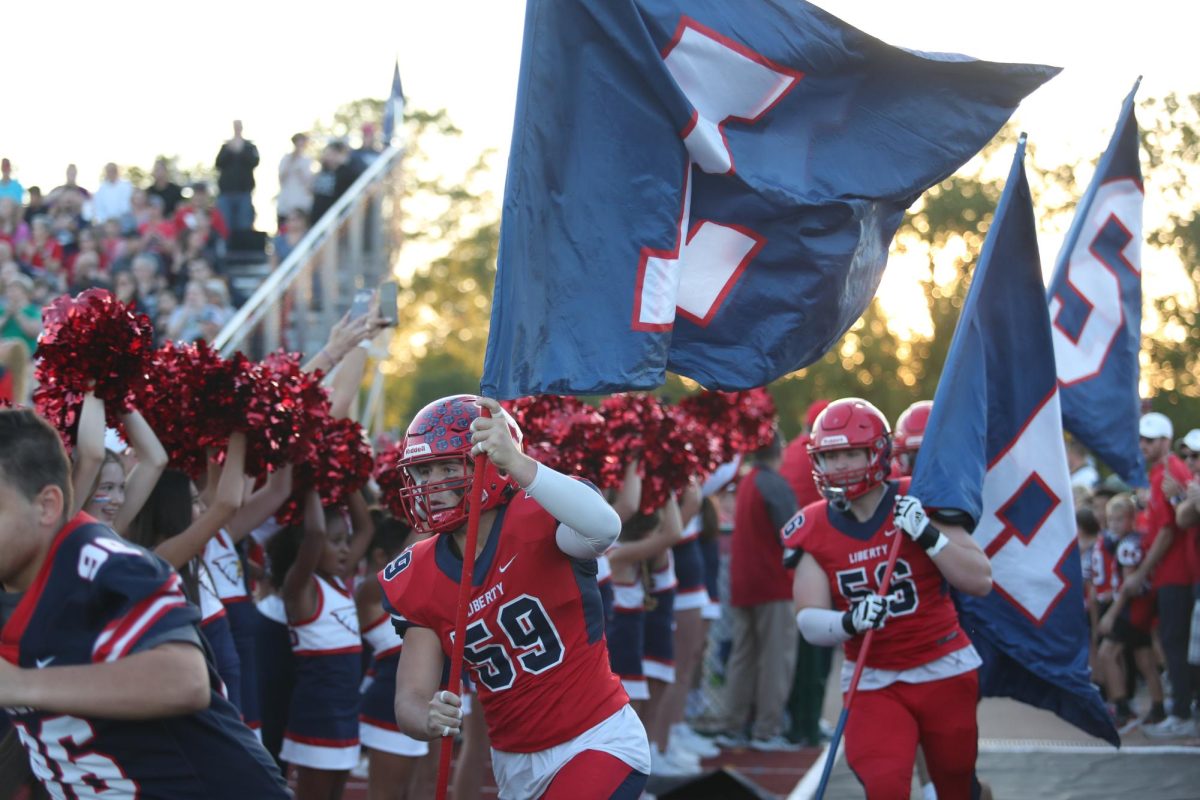Senior Drew Smith (#59) runs with a flag at the beginning of the game.