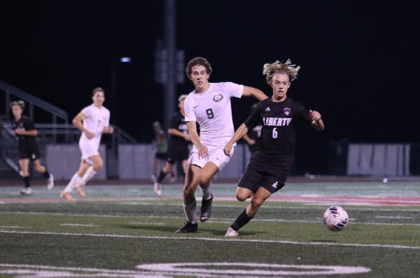 Junior Dylan Handlan (#6) chases the ball down the field while being chased by senior Chas Colbert (#9) from Rock Bridge. 