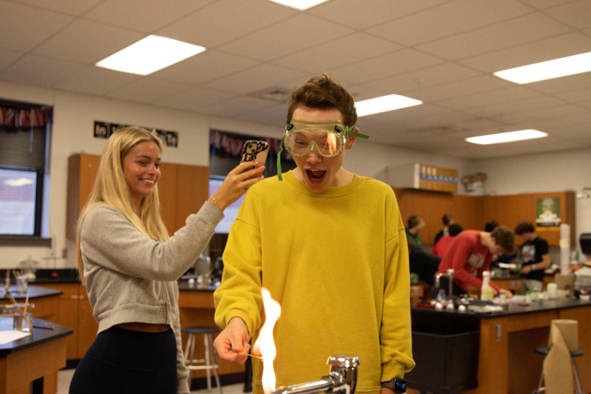 During a flame experiment in the introduction to biochemistry class, senior Addison Craven records sophomore Charles Girauds reaction as the flame shoots up.  