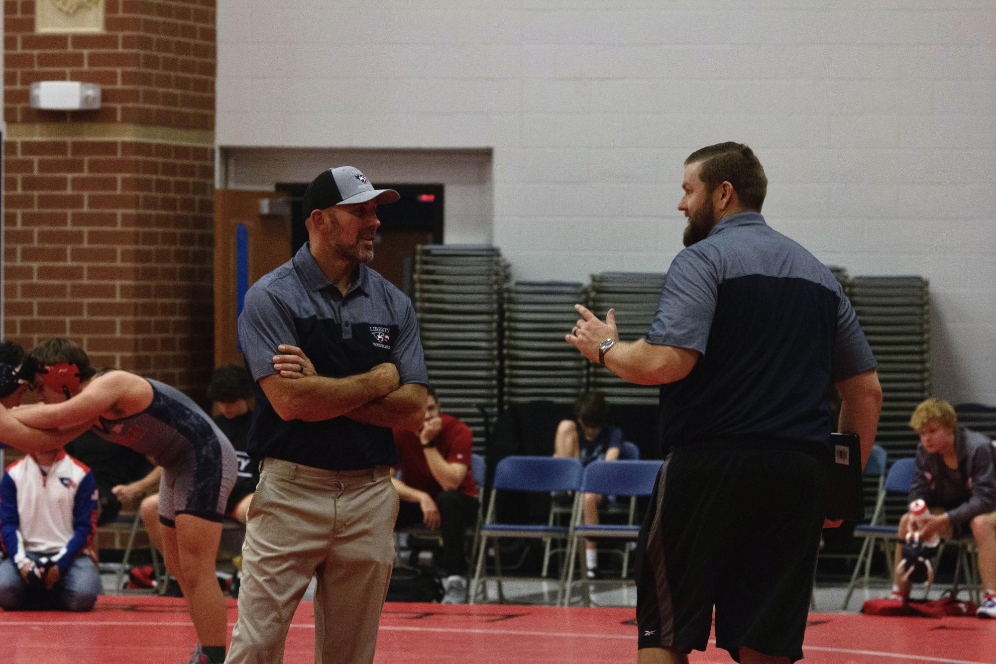 During the Jamboree, the wrestling coaches Haynes and Kling talk to each other about the ongoing match.