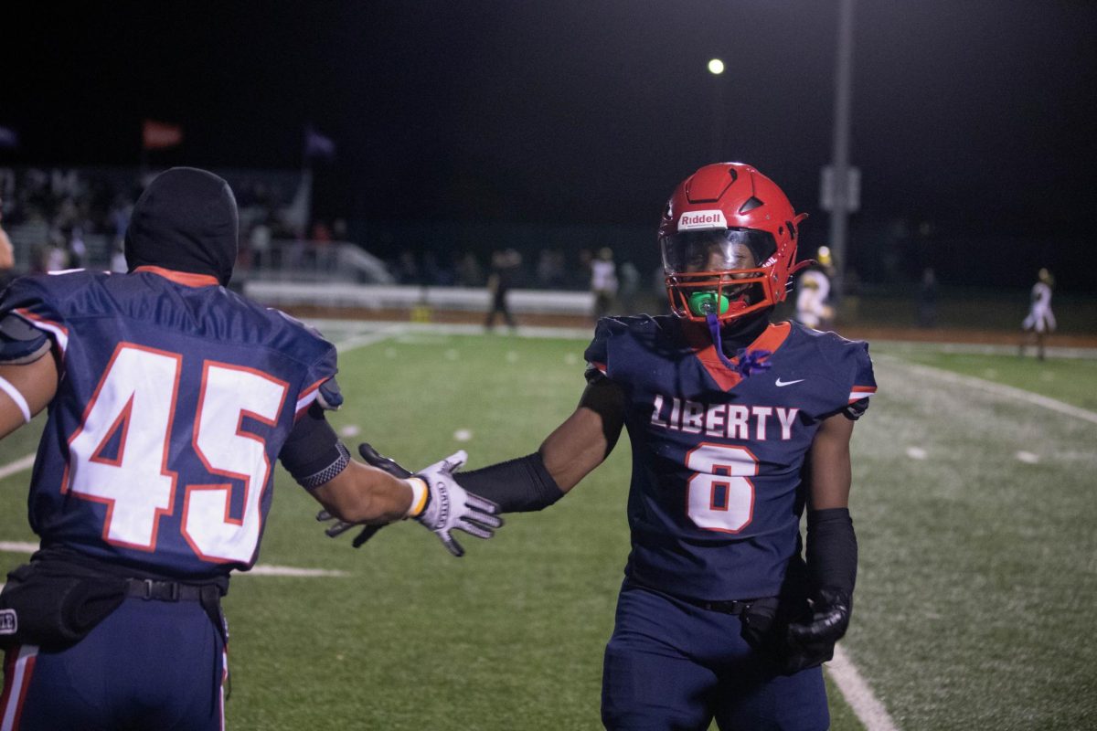 Junior Iker Cuevas and senior Marquis Williams go in for a handshake as Williams walks off to the sidelines. This was the first time in two years that Liberty hosted Francis Howell North on the home field, which resulted in a 49-0 victory, allowing Liberty to face Fort Zumwalt North on Nov. 3 for the second round of playoffs. 