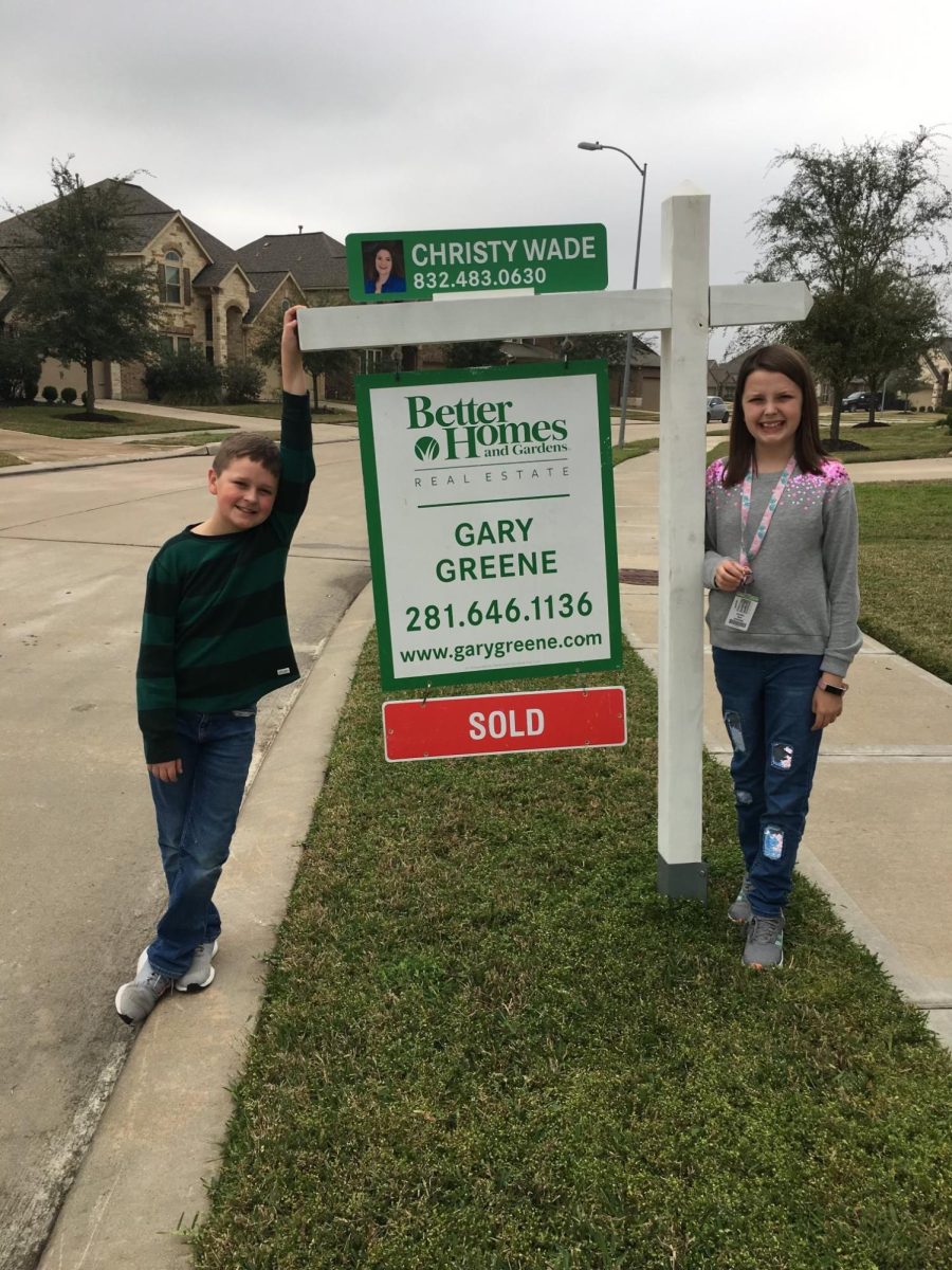 Me and my brother standing in front of the for sale sign at our old house in 2019.