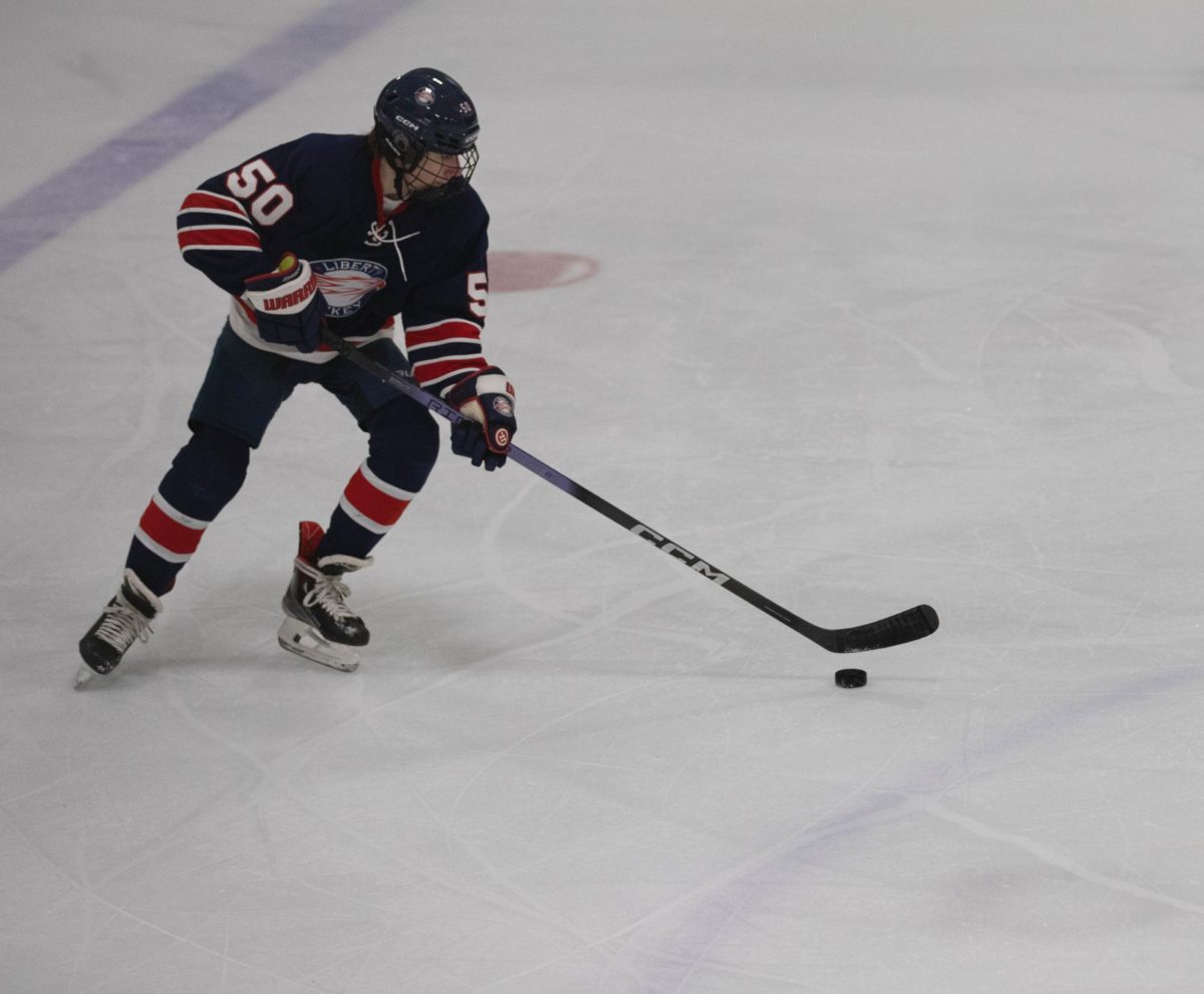 Sophomore Owen Johnson glides across the ice with the puck, which he would then pass along to a teammate.  