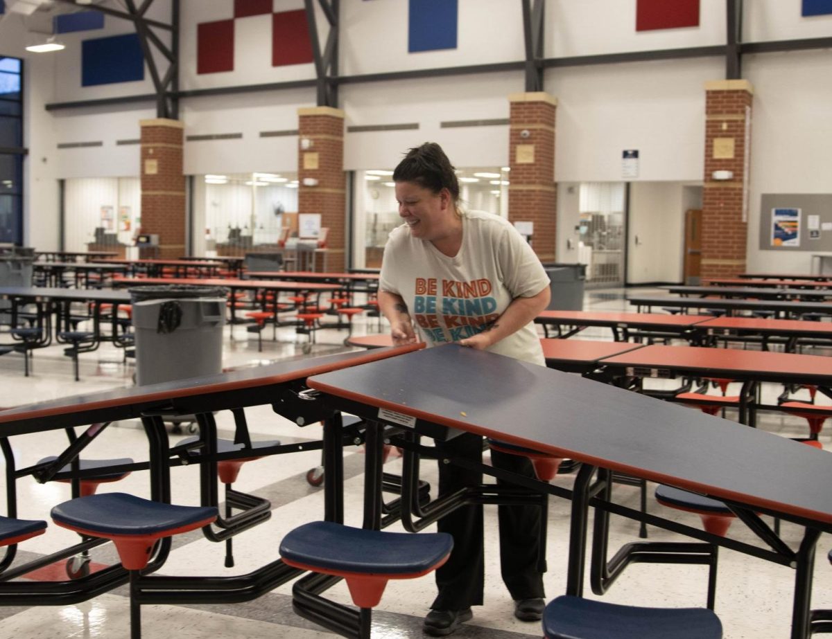 Custodian Leah Brunton helps put up tables so she can clean the floor before lunch starts.