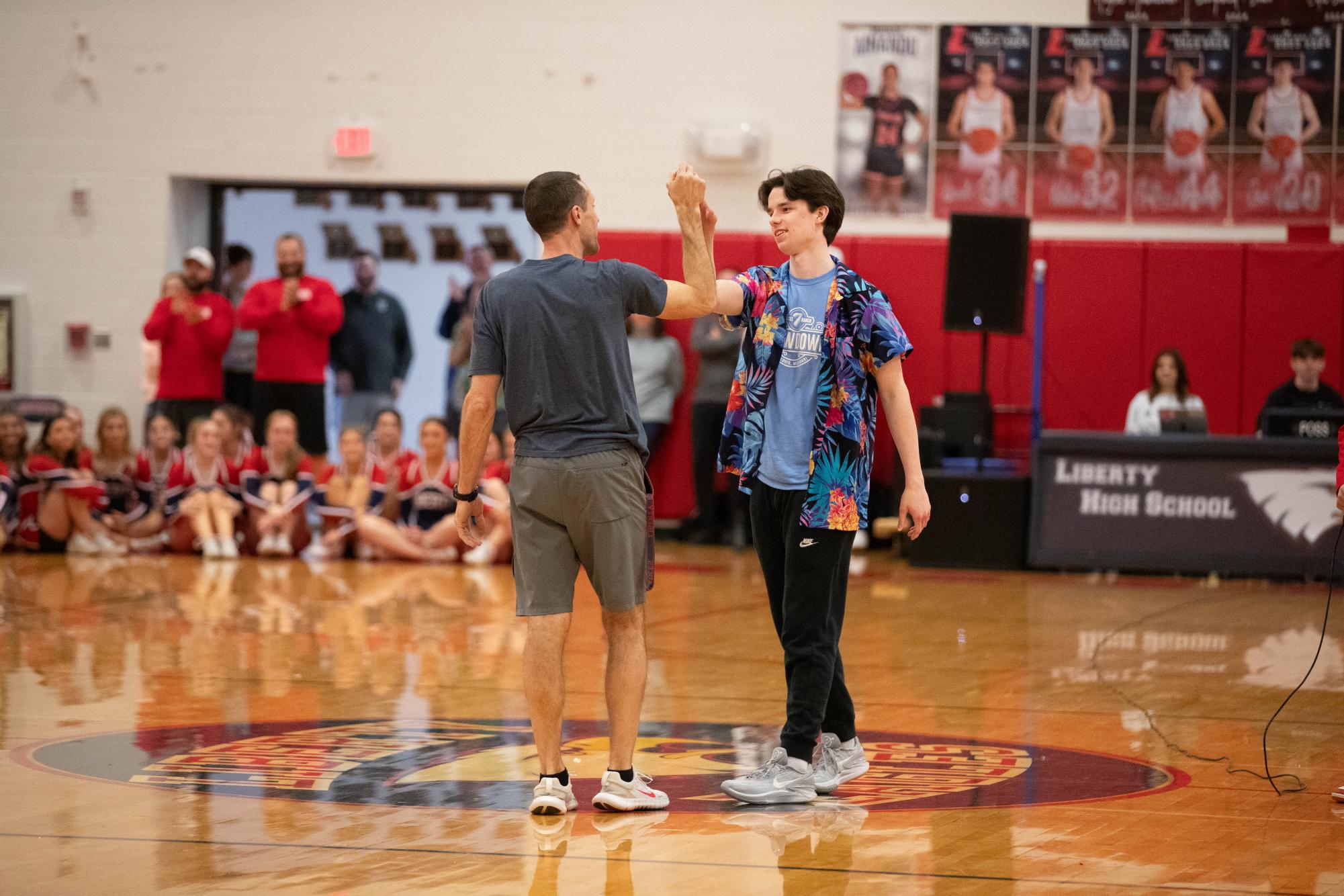 Mr. Sodemann goes in for a high five with senior Carter Ashby after an intense round of basketball during the annual Coaches vs. Cancer assembly. 