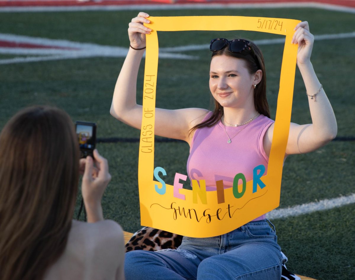 Samantha Irlmeier poses for a picture taken by her friend, using a frame made by the class officers.
