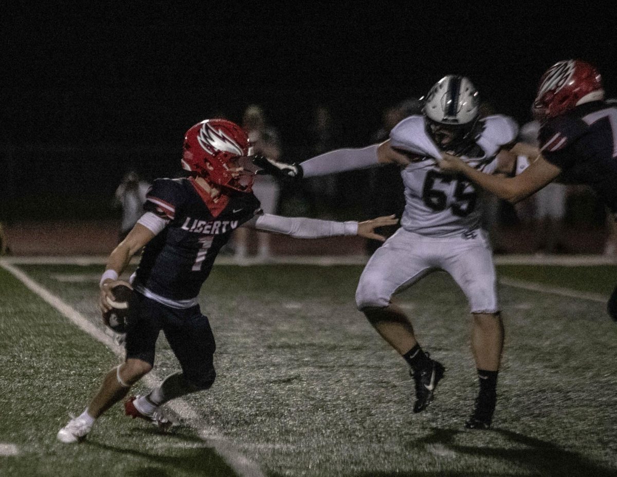 Quarterback Cody McMullen (12) escapes from a Howell Central defender during both team's opening season game. 