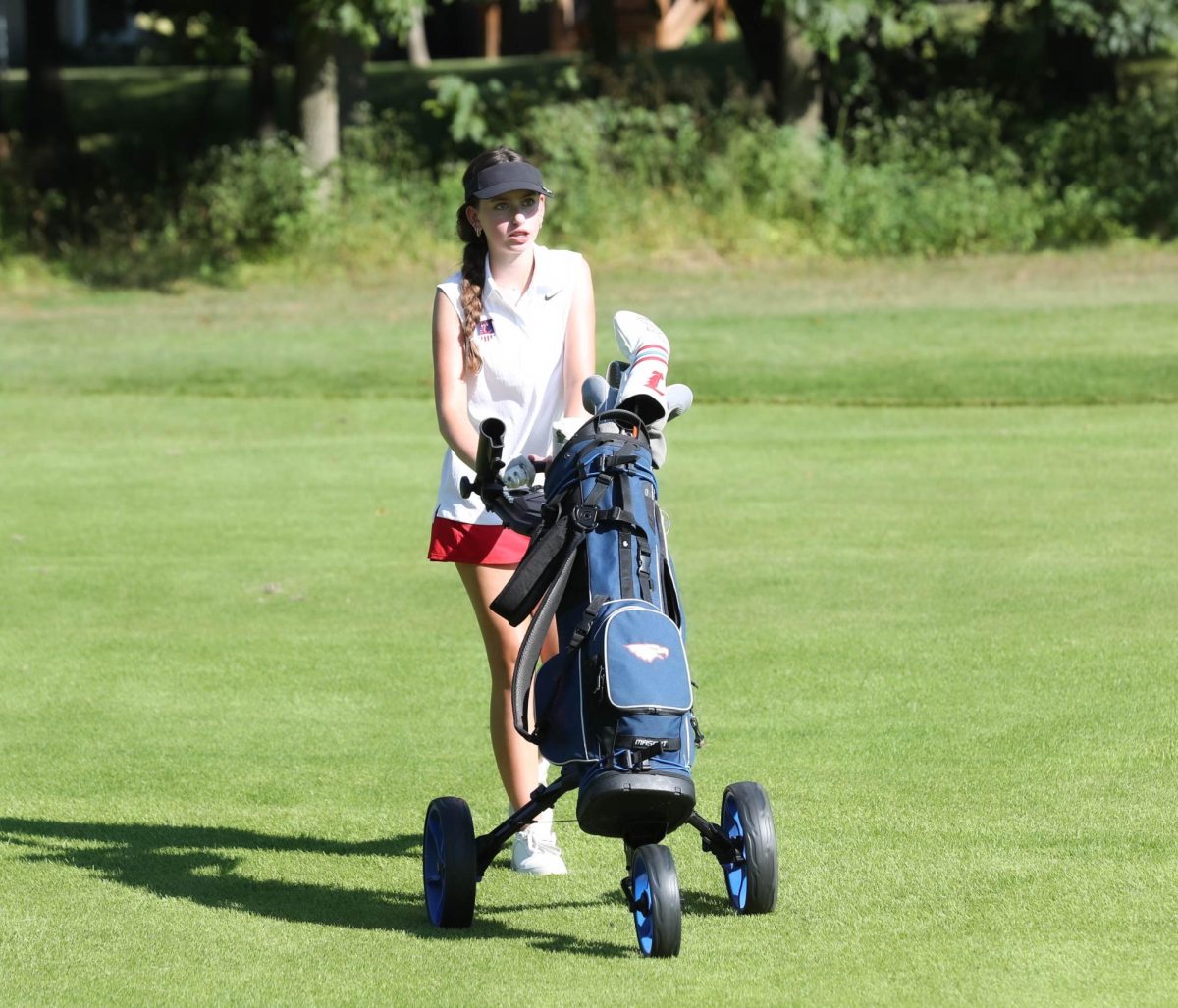 Jaime West (9) rolls her cart off onto the next green at the golf match against Troy Buchanan on Payton Lindsay (9) lines up her club to the ball on the rough during the golf match against Troy Buchanan on Sept. 5.