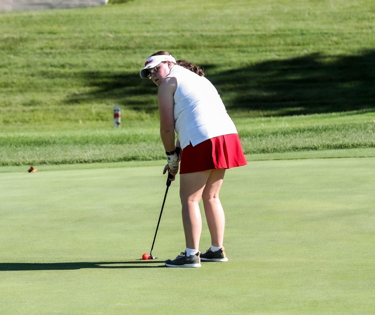 Lucy Bowen (12) brings her eye to the hole as she gets ready to swing her club at the golf match against Troy Buchanan on Sept. 5.