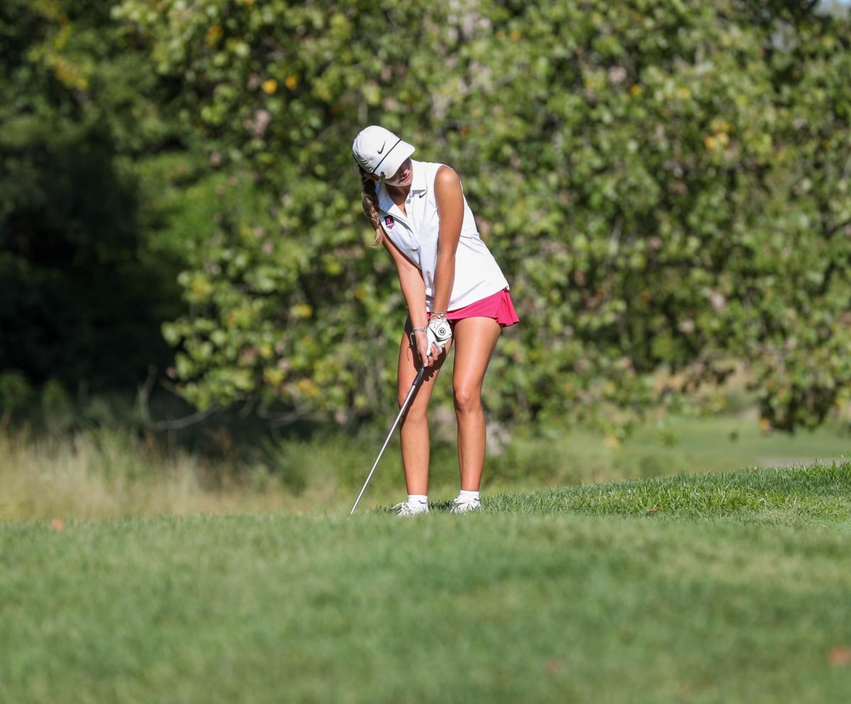 Payton Lindsay (9) lines up her club to the ball on the rough during the golf match against Troy Buchanan on Sept. 5