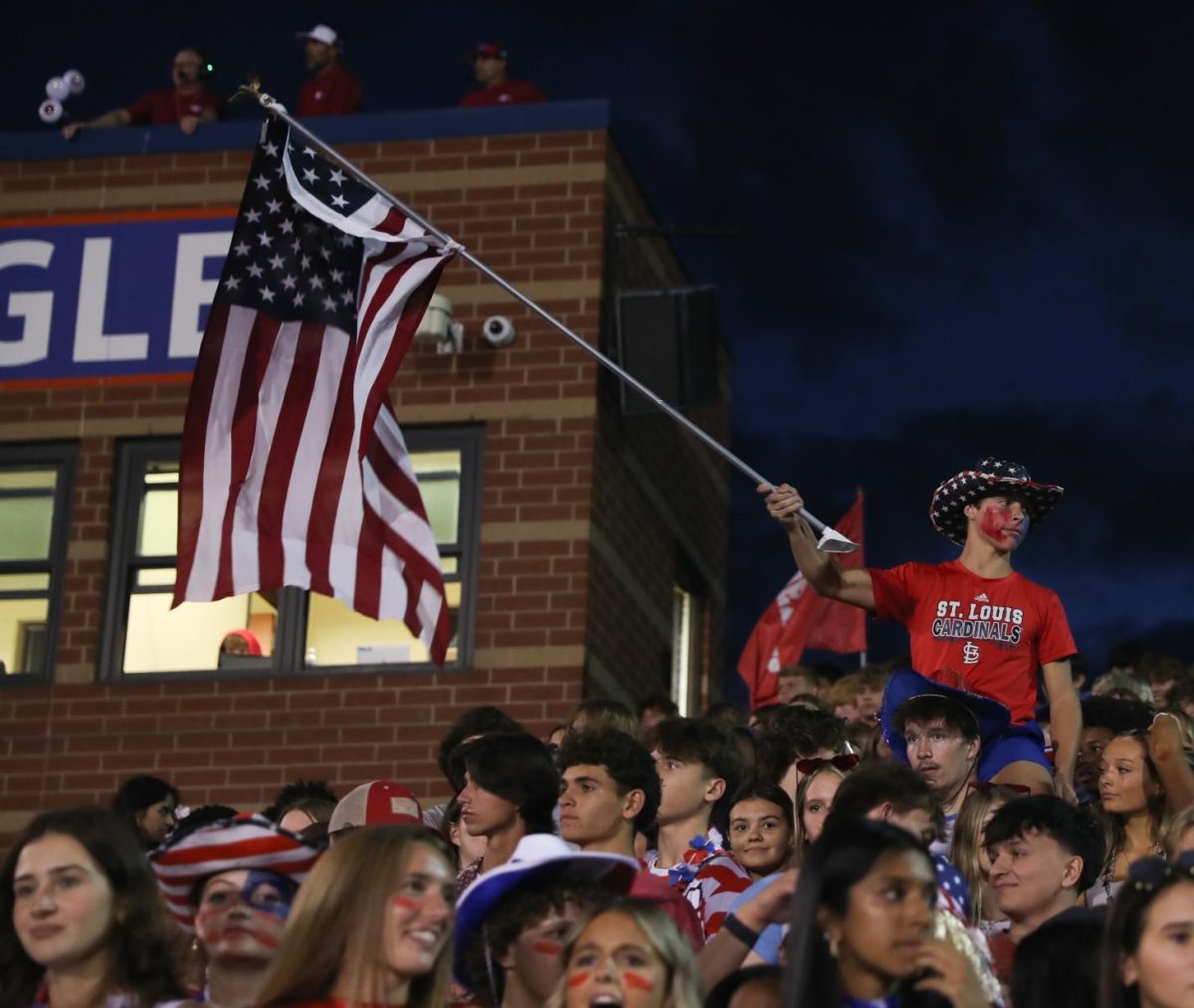 Nicholas Kuhn (10) waves an American flag while sitting on Mason Huebner's (12) shoulders.