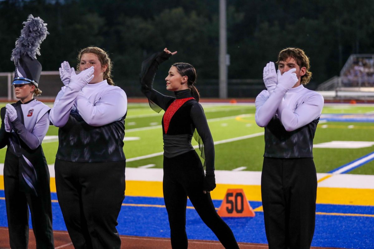 Drum Major Kylie Honerkamp (12), Color Guard Captain Kayla Milton (12), and Drum Major Ethan Hagner (12) salutes after receiving awards. They won second place guard and fifth place band at the Seckman Competition.