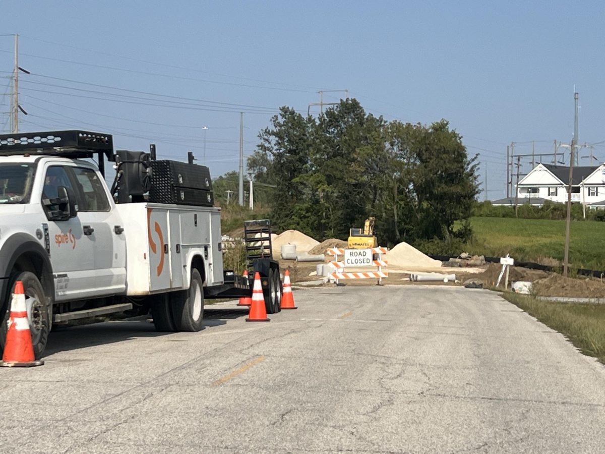 Road closure signs can are displayed near the construction site, along with utility trucks.