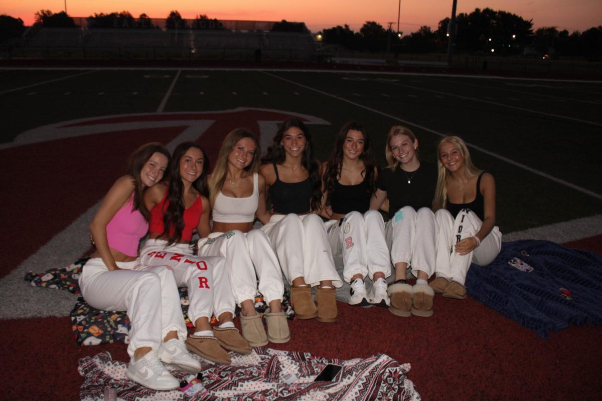 All smiles as seniors take a group photo with their friends huddling in close.