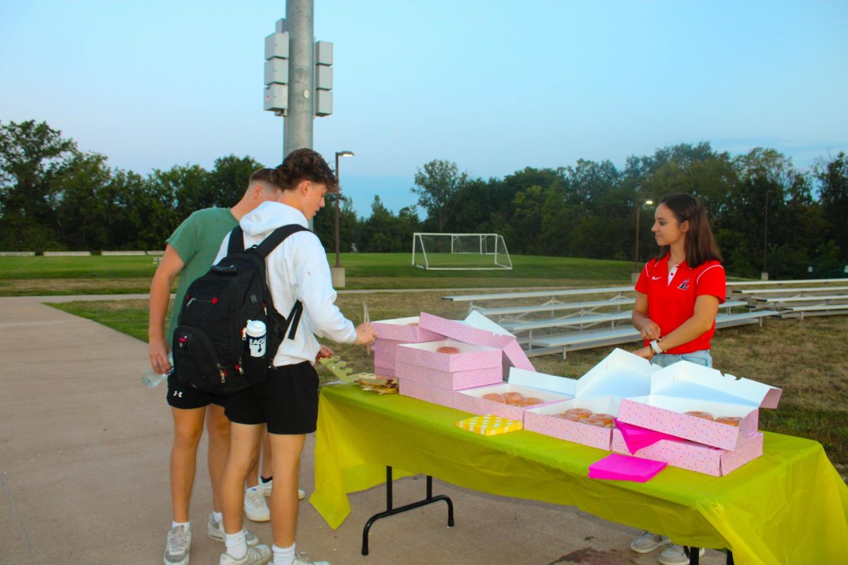 Mrs. Fedderson serves Sweet Spot donuts to students. 