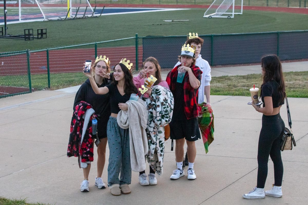 Seniors take a group selfie while holding their blankets and showing off their crowns.