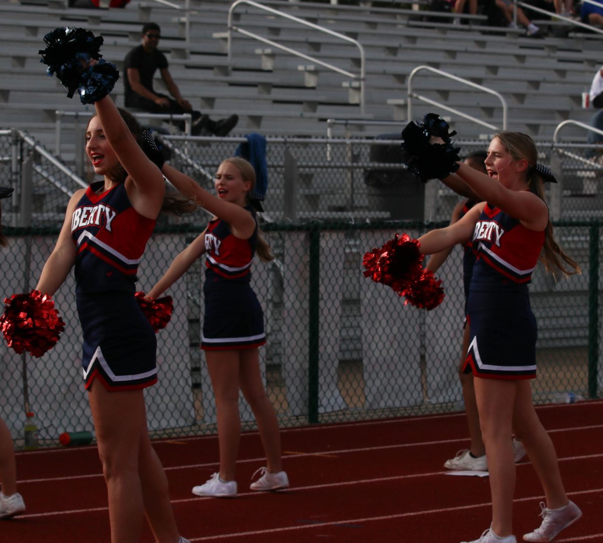 Ava Ackerman (9), Alaire Palmer (9), and Alayna Grygiel (9) cheer on the sidelines at C team football game.